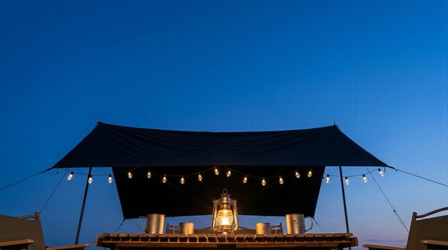 Cozy outdoor camping setup with vintage lantern and string lights under black canopy at twilight.