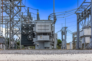 Low angle view of a large industrial power transformer with cooling fans at an electrical substation facility under a clear blue sky © Andrei Liashchou