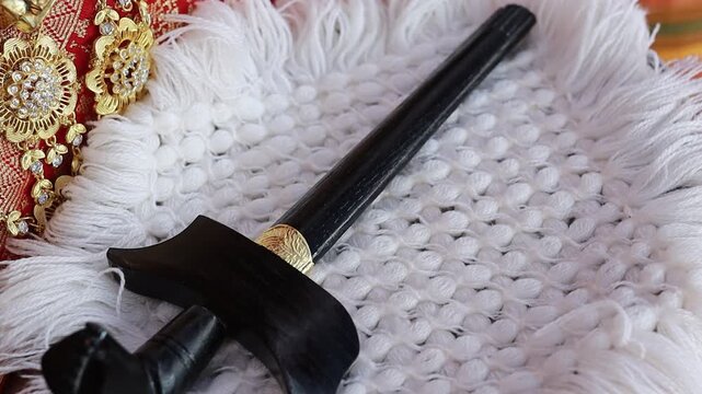 A traditional Keris dagger resting on a soft white fluffy cloth, highlighting the detailed craftsmanship of the blade and handle as a symbol of Indonesian ceremonial and cultural heritage.