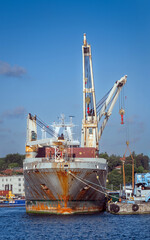 Fototapeta premium A old ship unloading or loading cargo at the port.