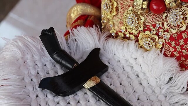 A traditional Keris dagger resting on a soft white fluffy cloth, highlighting the detailed craftsmanship of the blade and handle as a symbol of Indonesian ceremonial and cultural heritage.
