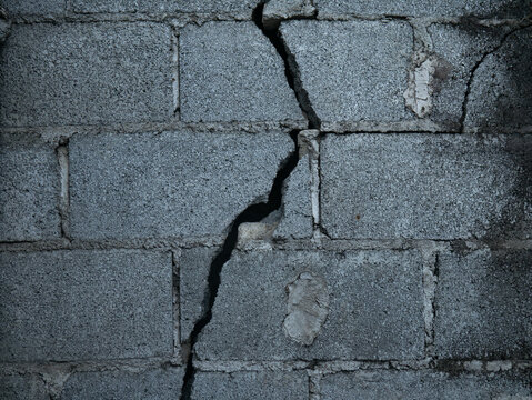 Weathered Grey Concrete Block Wall Large Diagonal Crack Close Up Urban Decay Structural Damage Grunge Texture Background Portrait