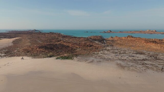 Cobo Bay Guernsey Channel Islands.View from golden sandy beach out to sea over pink granite rocks towards calm sea and rocky outcrops on sunny day with clear blue sky