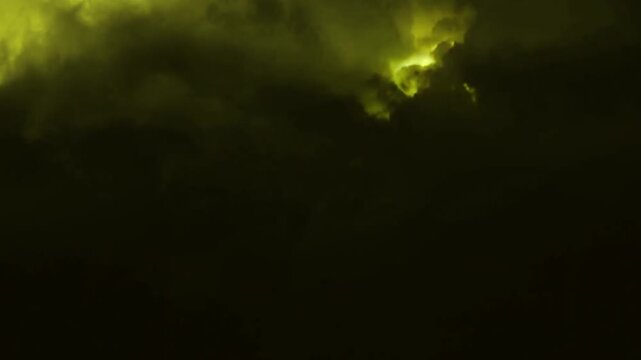 Dramatic yellow lightning bolts flashing in the dark night sky with heavy clouds