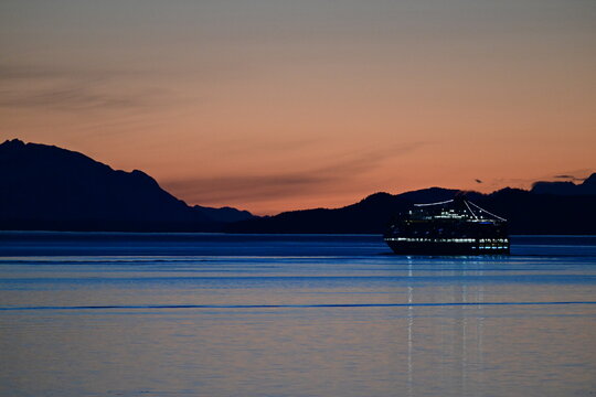 magical natural sunset colors in the interior passage of Alaska, smalls ship cruise passes by