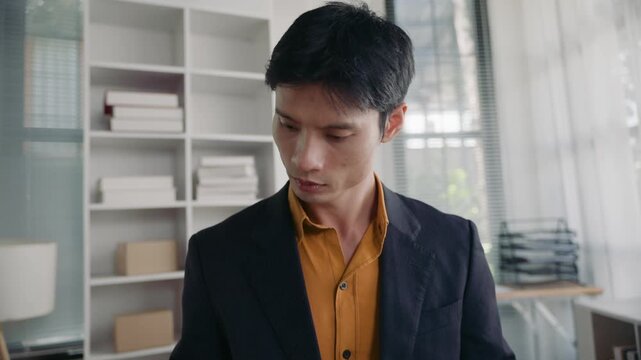 Focused Asian businessman checking and analyzing business reports with charts and graphs. Professional man working with financial data at his desk
