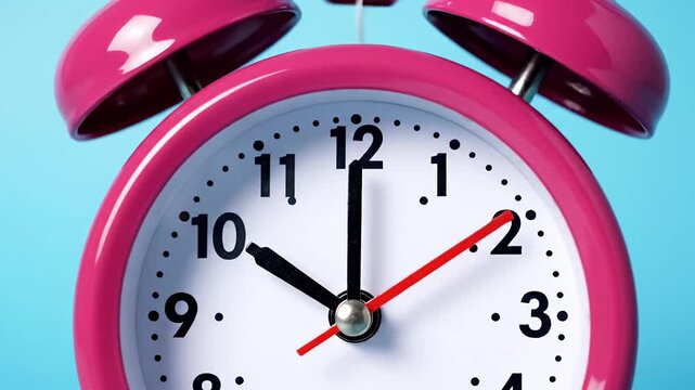 Pink twin bell alarm clock on blue background.