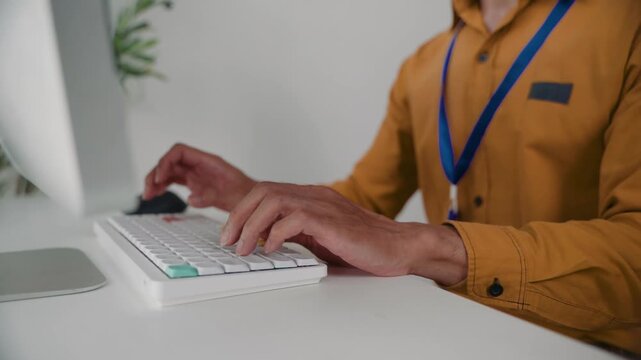 Close-up of a corporate worker's hands typing on a computer keyboard. Unrecognizable male employee using a modern peripheral at his workplace