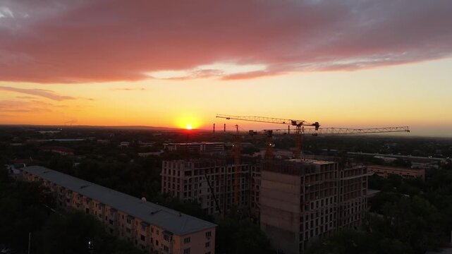 Construction site at sunset with cranes and buildings under development