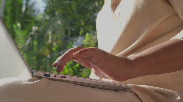 Man typing on laptop while working outdoors in peaceful natural setting, showcasing focused remote work, digital productivity, deep concentration, flexible work lifestyle, and modern mobile office