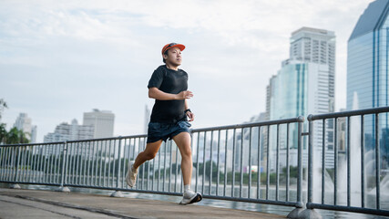 Obraz premium Adult asian athlete man runner training for marathon challenge male wear sports outfit running workout exercise at outdoors urban lifestyle