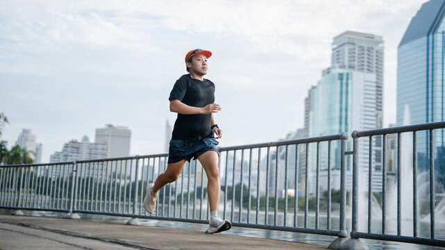 Adult asian athlete man runner training for marathon challenge male wear sports outfit running workout exercise at outdoors urban lifestyle
