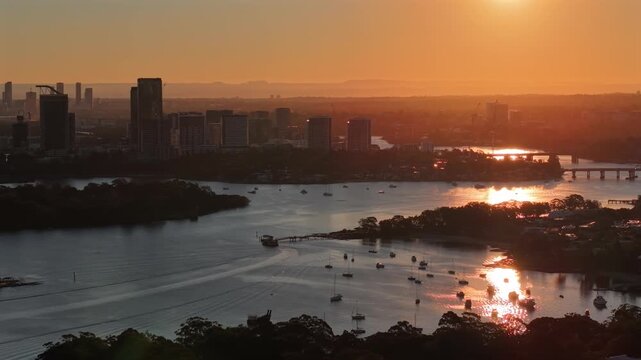 Aerial drone video over Rhodes, Sydney, revealing Parramatta in the background at sunset, with waterfront apartments, river views, and warm evening light.