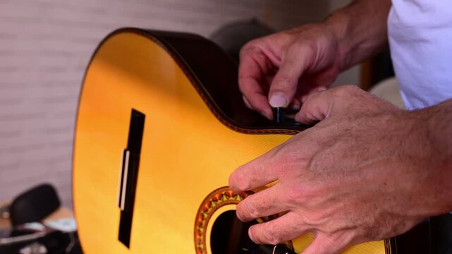 Close up of a man placing a soundhole pickup on an acoustic guitar