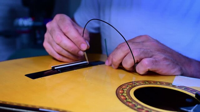 Close-up of a luthier changing a classical guitar string