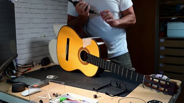 Luthier carefully repairing a classical guitar with a rotary tool
