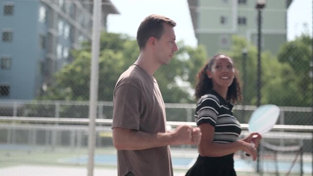 Male and female pickleball players are walking and discussing training programs and competition schedules, as well as how to maintain their physical condition in preparation for tournaments.