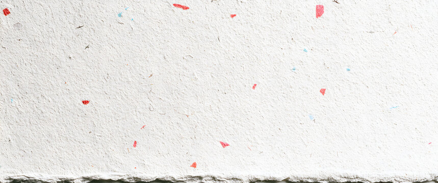 White handmade paper with subtle fiber textures and small colorful flecks. Organic and recycled mulberry paper with a background concept for craft art