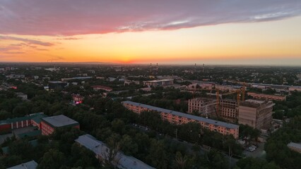 Obraz premium Aerial view of cityscape at sunset with construction site and buildings