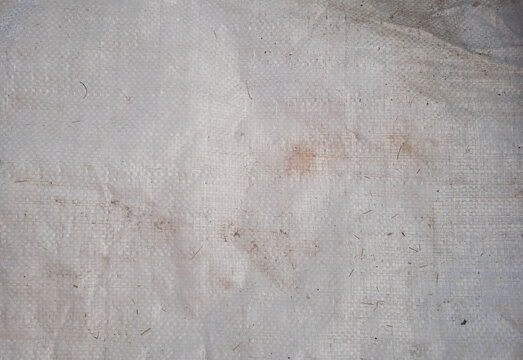 full frame texture of a dirty old white woven plastic rice sack with stains