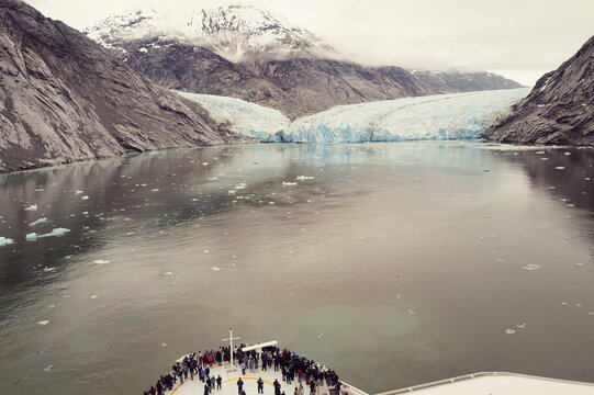 Dawes Glacier from cruise ship view with tourists viewing wild Alaska from the front deck