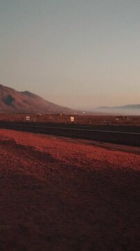 Vertical pan from a desert highway with passing truck at dusk to arid mountains and scrubland