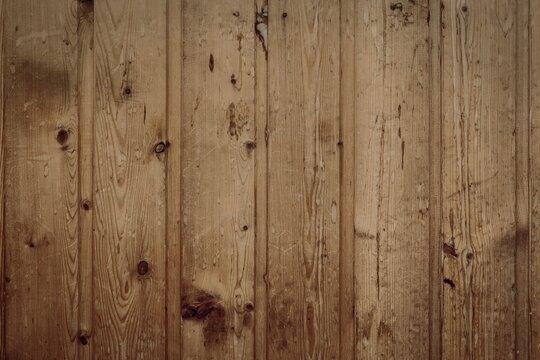 Weathered vintage wooden panel texture with knots and vertical planks. Natural grain patterns, scratches, water stains and aged imperfections.