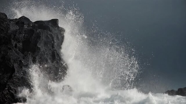Ocean wave crashing against volcanic rock with splash and sea foam