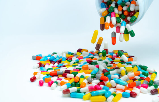 Pouring capsule pills from plastic drug bottle to white table. Pile of colorful capsule pills. Pharmaceutical industry. Healthcare and medicine background. Pharmaceutics concept. Drug interactions.