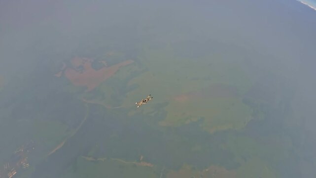 Two military parachutists in camouflage perform a joint free fall during aerial training. Shooting from a high altitude above the clouds.
