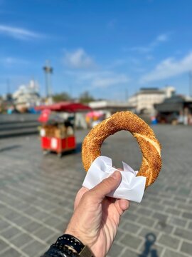 A man holding a traditional Turkish bagel - Simit