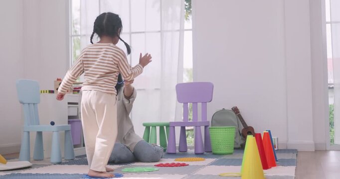 Happy Asian mother and daughter playing a colorful ring toss game together indoors.