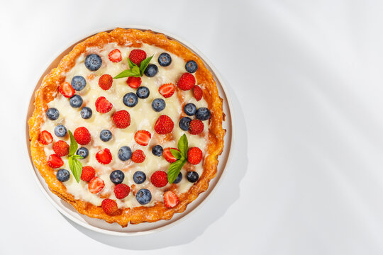 Homemade berry tart topped with fresh raspberries and blueberries