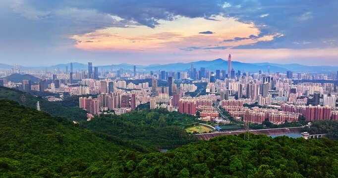 Aerial view of Shenzhen city skyline with lush green forest at sunset, China