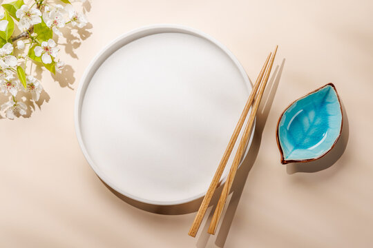 Empty white plate with chopsticks and blue bowl