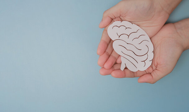 Gentle hands hold paper brain symbol with hope demonstrating inclusive medical care and supportive empathy for mental health awareness