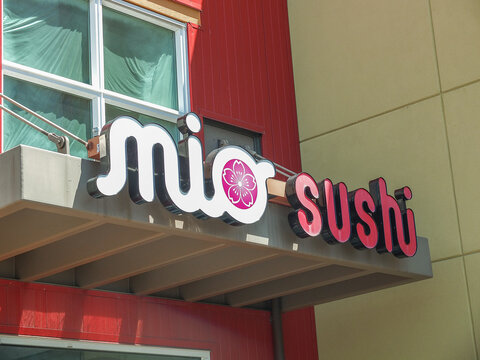Mio Sushi restaurant exterior neon sign on a modern red and beige building facade in Ruston.- June 13, 2026 Ruston WA, USA