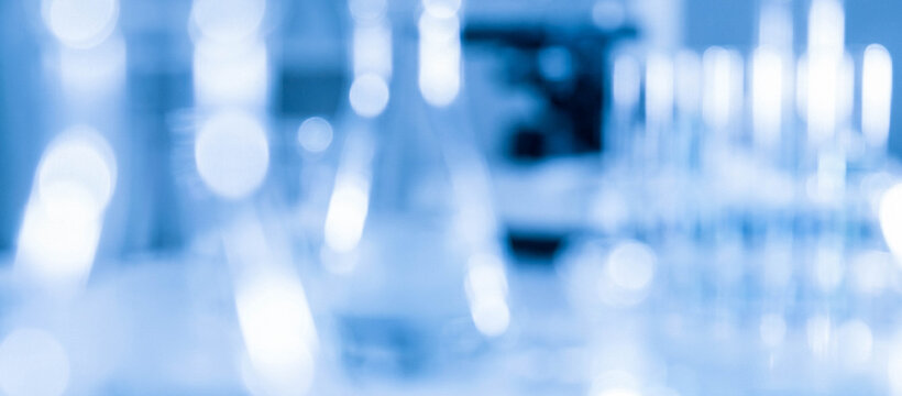 Blurred laboratory glassware creates an abstract background of scientific equipment, highlighting the essence of research and experimentation in a lab setting.