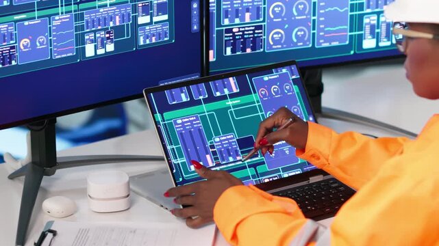 Engineer Carefully Monitors Hydropower System Data Using Laptop