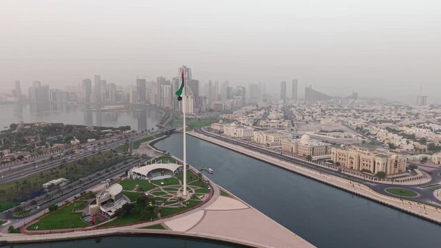 Cinematic Aerial Drone shot of Sharjah at early morning golden hour, UAE Flag, Sharjah Skyline and Sharjah Corniche in the background