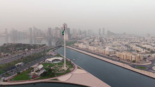 Cinematic Aerial Drone shot of Sharjah at early morning golden hour, UAE Flag, Sharjah Skyline and Sharjah Corniche in the background