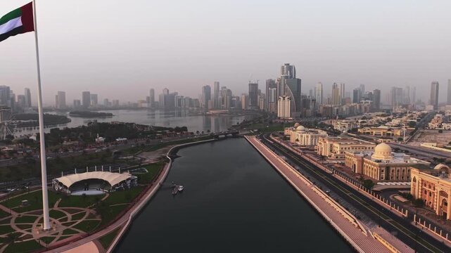 Cinematic Aerial Drone shot of Sharjah at early morning golden hour, UAE Flag, Sharjah Skyline and Sharjah Corniche in the background