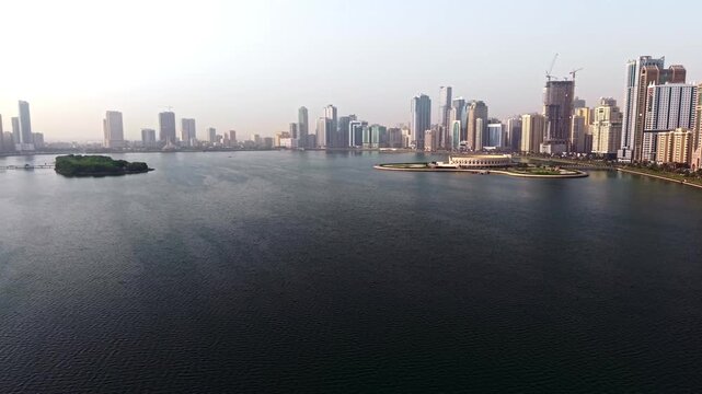 Cinematic Aerial Drone shot of Sharjah at early morning golden hour, UAE Flag, Sharjah Skyline and Sharjah Corniche in the background