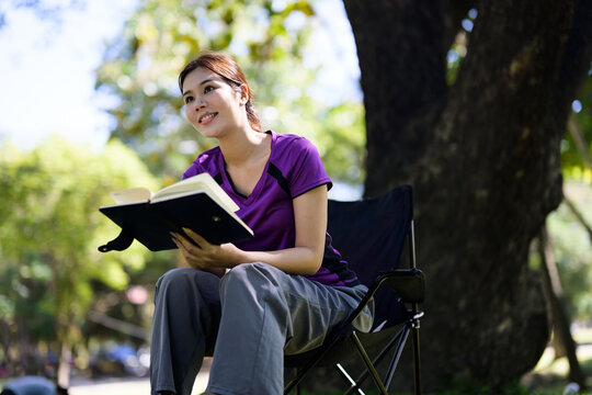 Young woman enjoying reading book in park