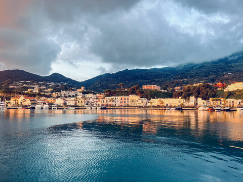 scenic sunrice seen from ocean at harbor at Lacco Ameno at the island of Ischia with sailing yachts