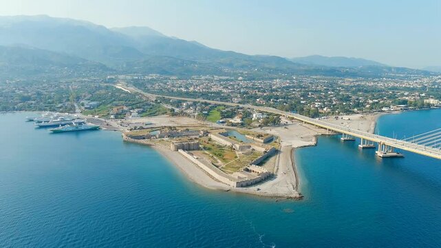 Patras, Greece. Rio Fortress and the Charilaos Trikoupis Bridge, a pentagonal Ottoman fortification beside the world's longest multi-span cable-stayed bridge, Drone footage over the Gulf of Corinth. 