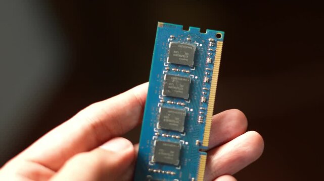 Close up of a hand holding a blue computer memory ram stick for hardware upgrade and digital performance enhancement