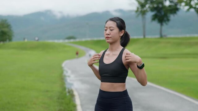Young woman warming up and stretching her upper body before exercise on an outdoor running track, representing fitness preparation, healthy lifestyle, preventive health and longevity concept.