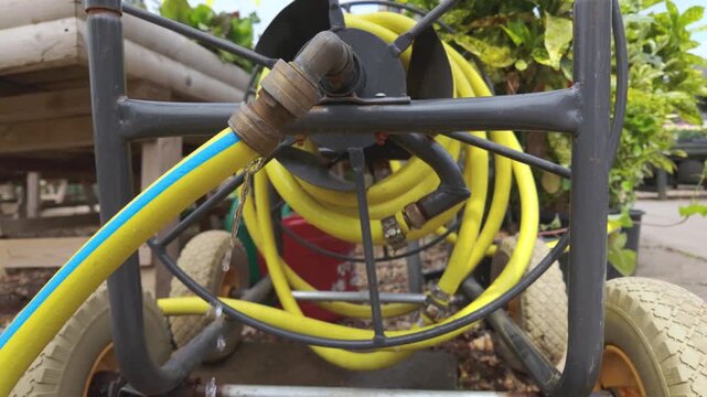 Close view of a garden hose leaking at the connector while water drips from the fitting inside a greenhouse. High quality 4k footage