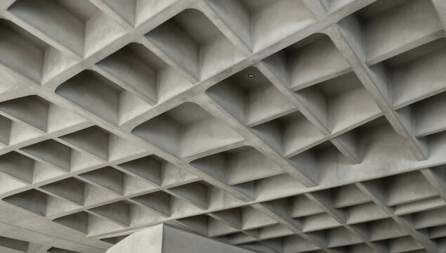 Geometric Concrete Ceiling: A close-up view of a modern concrete ceiling with a repeating geometric pattern of squares and recesses, showcasing the architectural design.